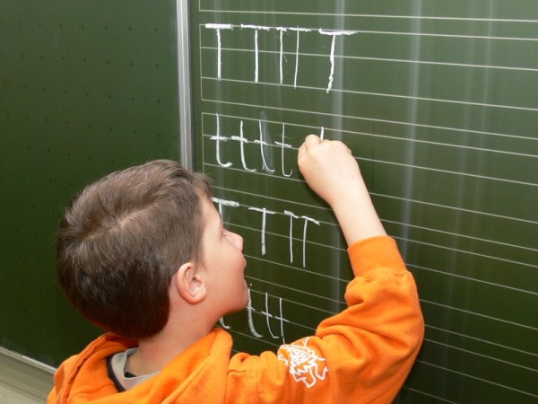 Buchstabe in die Lineatur an der Tafel schreiben